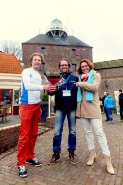 Ruud Jansen, organisator van de Halve Marathon van Harderwijk, ontvangt een bloemetje uit handen van Ilonka Donker (rechts) en Marcel Companjen (links)